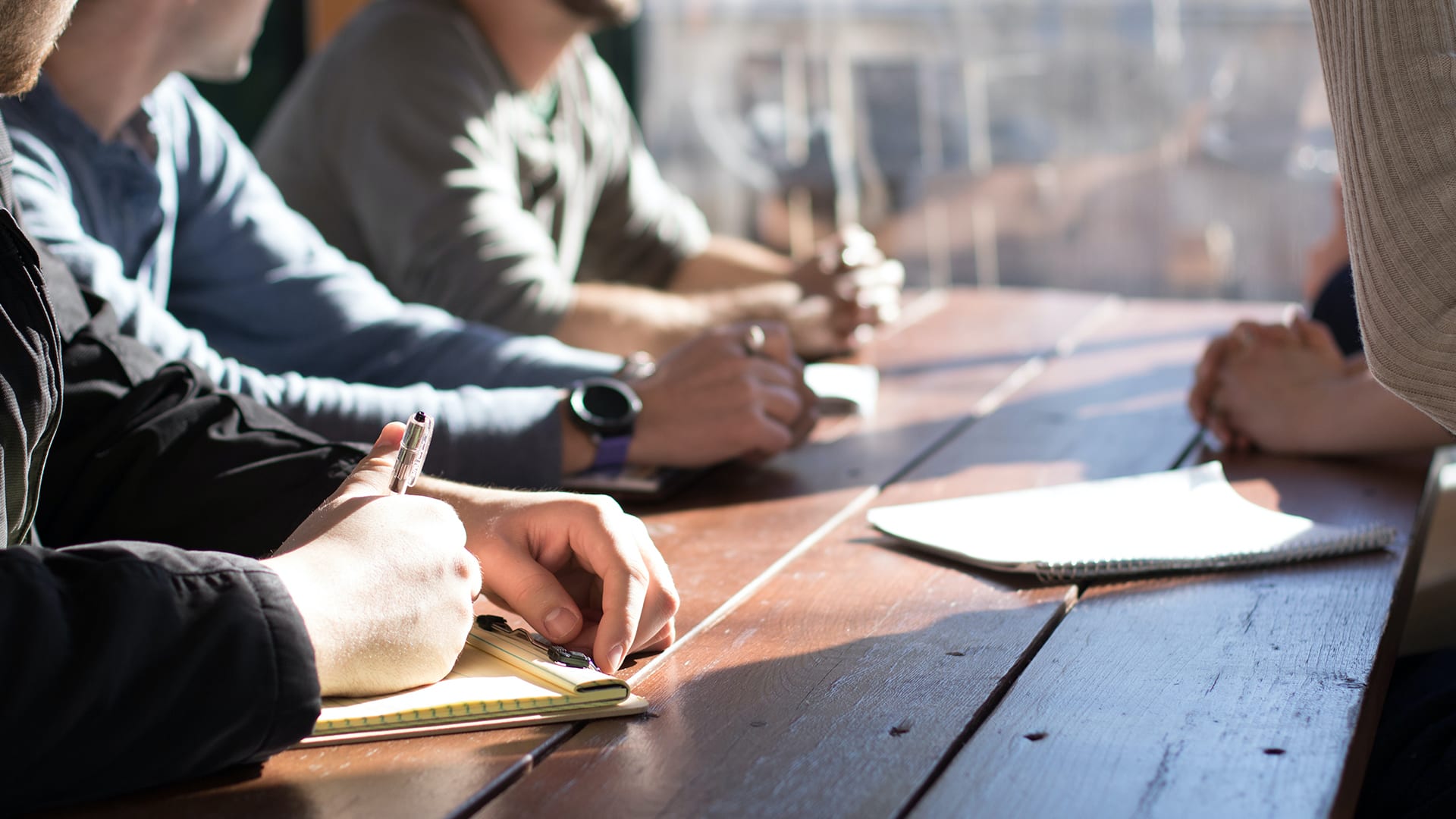 people-sitting-on-chair-in-front-of-table-while-holding-pens-during-daytime people sitting on chair in front of table while holding pens during daytime